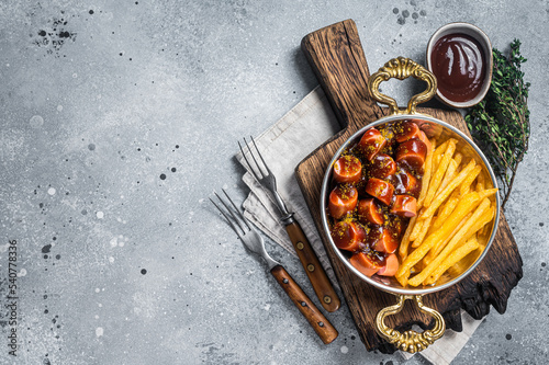 Traditional German currywurst sausage, served with chips or French fries in a pan. Gray background. Top view. Copy space photo
