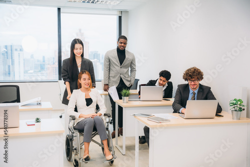 Businesswoman holding a meeting, conference, and conversation with his team while seated in a wheelchair at the workplace.