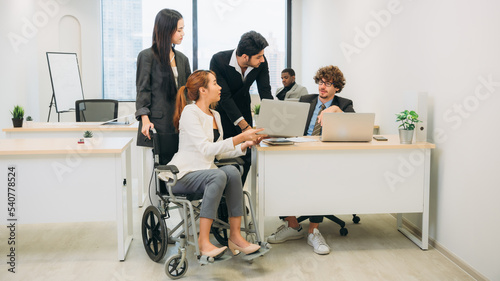 Businesswoman holding a meeting, conference, and conversation with his team while seated in a wheelchair at the workplace.