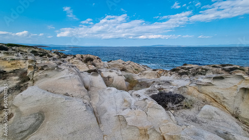 Rocky seashore before sunset near Karydi beach, peninsula Sithonia, Chalkidiki (Halkidiki), Greece, Europe. Distant scenic view of Mount Athos. Rock formations along Aegean Mediterranean coastline photo
