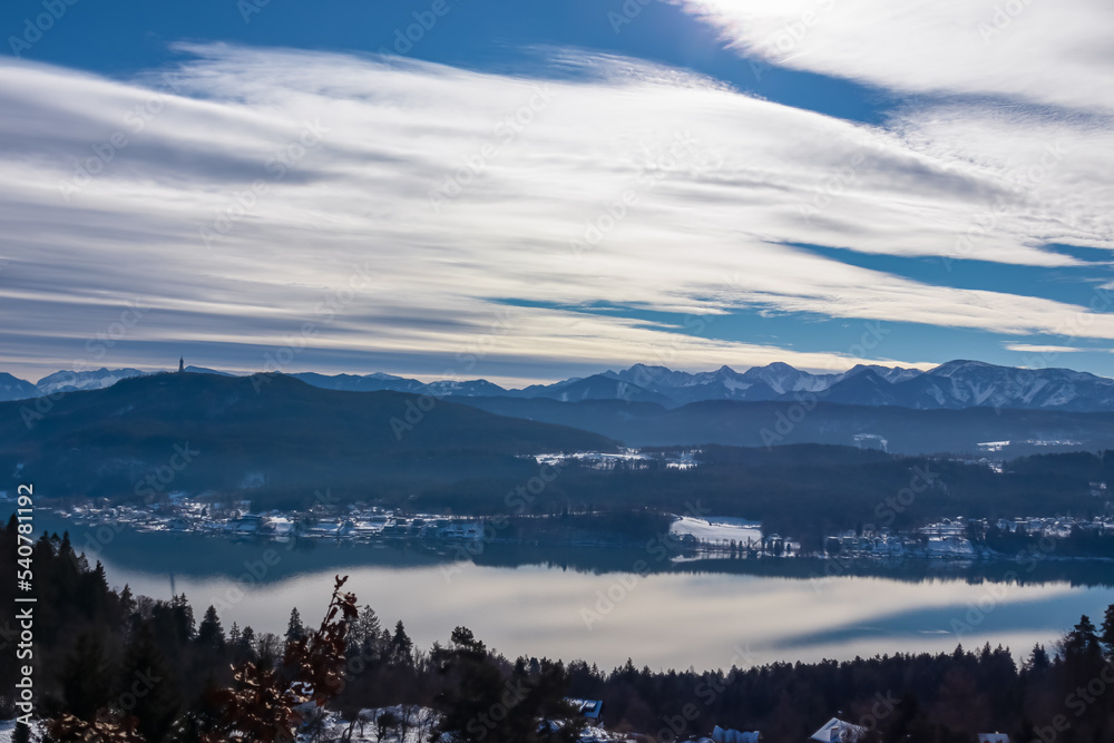 Panoramic view of the lake Woerthersee (lake Worth), tower Pyramidenkogel and snow capped Karawanks mountain range near Techelsberg, Carinthia (Kaernten), Austria, Europe. Winter wonderland in Alps