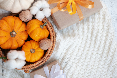 Autumn mood wallpaper with space for text on bright white background. Orange baby pumpkin in bohemian basket. Crafty decorated gift box, modern eco gift. Thanksgiving day greeting card. Invitation