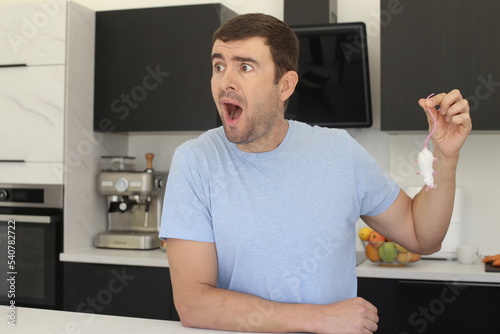 Obraz na plátne Man catching a mouse in his kitchen