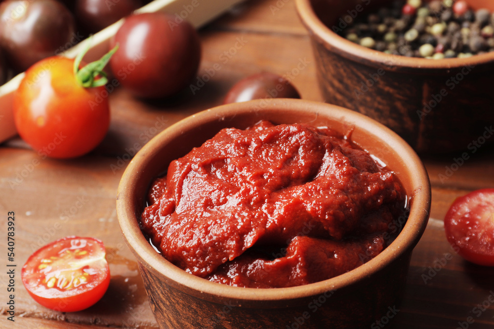 Bowl full of tomato sauce, Wooden spoon full of tomato sauce, spices, seasonings, Sliced ripe cherry tomato slices,  