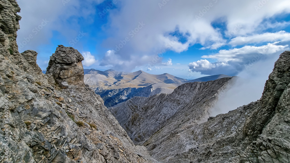 Trekking on mystical hiking trail leading to Mount Olympus (Mytikas, Skala, Stefani) in Mt Olympus National Park, Thessaly, Greece, Europe. Panoramic view of the cloud covered slopes and rocky ridges
