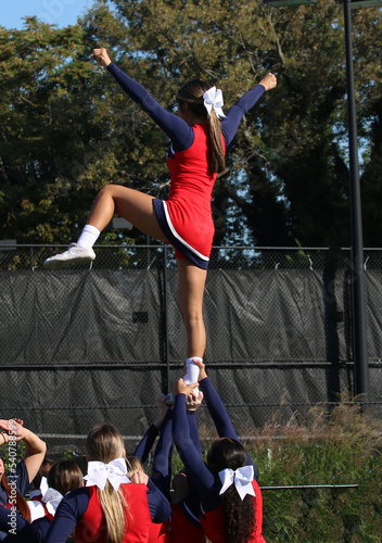 Canvas Print Cheerleaders in a pyramid holding teammate up in the sir by her ankle