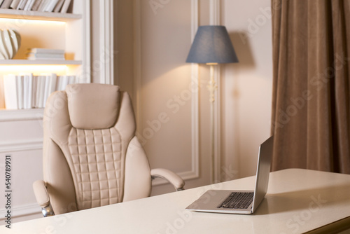 modern interior is in light beige tones. a table with a computer  an armchair  a floor lamp.