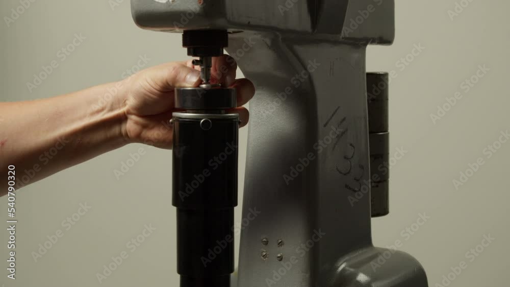 Worker checks metal detail hardness with durometer in laboratory macro view. Products quality control with equipment