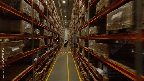 High racks with cardboard boxes and forklift loader in spacious warehouse first point view. Plant products storage