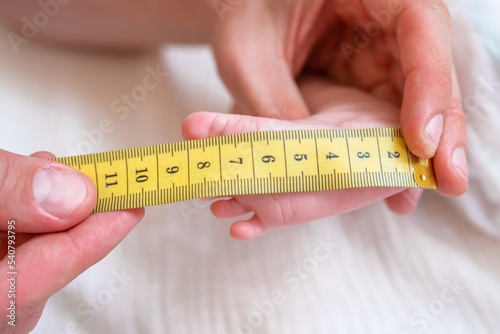 The baby's foot is measured with a measuring tape. choosing the size for shoes