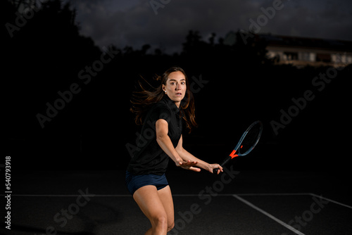 great shot of active female player with tennis racket on the outdoor tennis court.