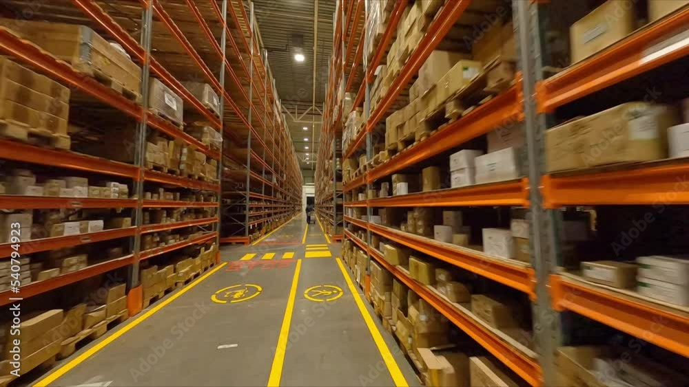 Forklift truck racks with boxes and worker pulling trolley in spacious warehouse first point view. Plant products storage