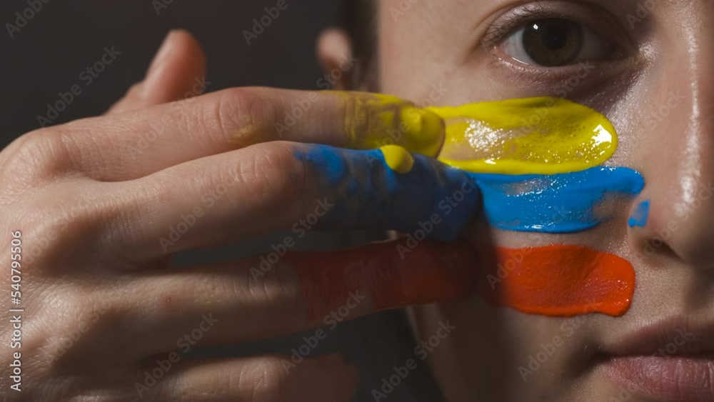 Supporter Painting Face and Looking at Camera. Football Fan Preparing for the Match. Colored Face with Flag Colors Yellow, Blue and Red. Slow Motion 4K Prores 422