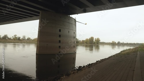 looking past the concrete pillar of a trough bridge viewed from the river bank