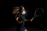 Close-up side view of excited woman with brown flowing hair in black tennis uniform with tennis racket