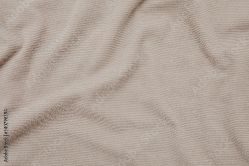 Creased and wrinkled fabric texture closeup. Beige shirt material. Flat lay, top view. 