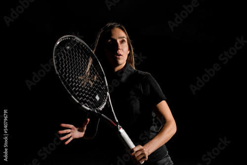 awesome beautiful portrait of caucasian woman with brown hair in black tennis uniform with tennis racket © fesenko