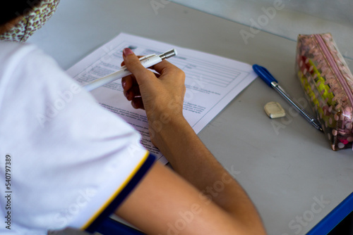 Student taking exam with school supplies on the table. photo