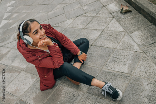 latin girl in the street with headphones listening to music