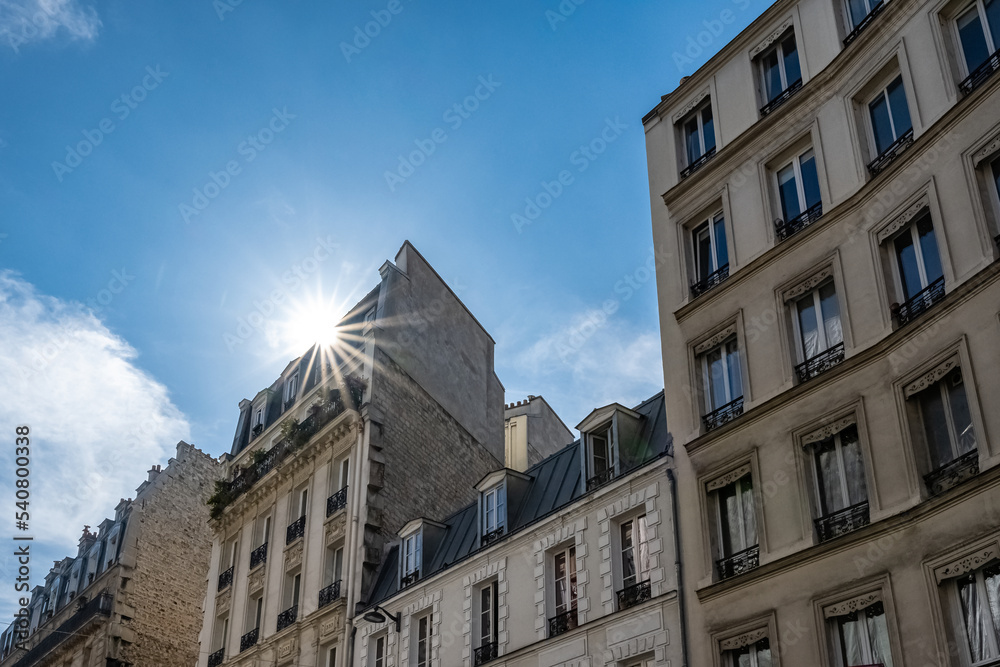 Paris, typical facades, beautiful buildings in Montmartre, sun’s rays 
