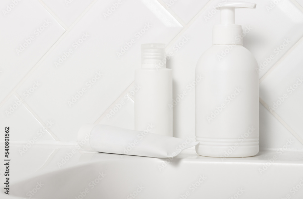 A set of white cosmetic jars with cream, toothpaste and shower gel in the bathroom on the sink. Cosmetics for face and body care. Home skin and hair care A set of white cosmetic jars with cream, toothpaste and shower gel in the bathroom on the sink. Cosmetics for face and body care. Home skin and hair care