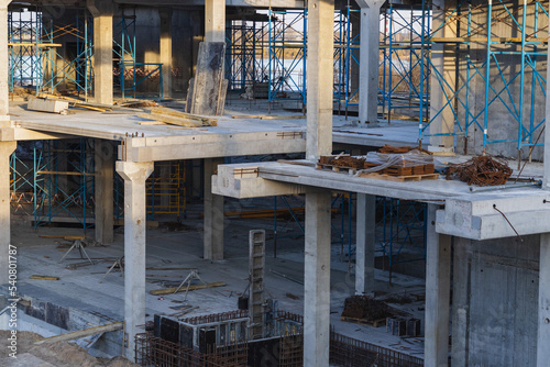 Crane and building under construction against blue sky on lake bank. Urban landscape