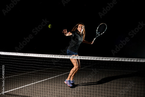 great shot of tennis ball in air and female tennis player with racket ready to hit it © fesenko