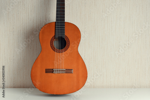 Classical acoustic guitar on a light wall background. 
