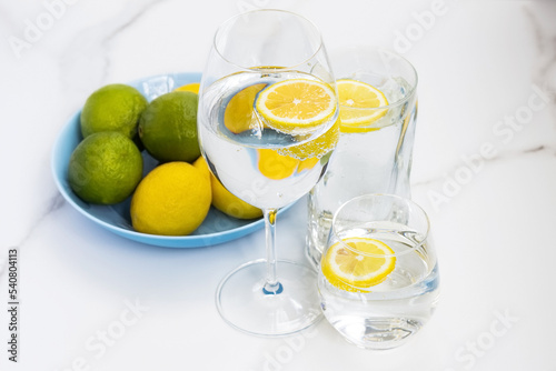 A glass of water, lemon and mint and lime on a white table for healthy life, energy, thermoregulation and normalization of digestion