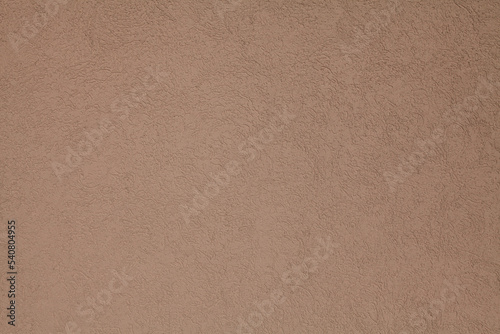 Brown, terracotta texture and background. Decorated surface with round ornamental embossed pattern. Pale light-brown wall surface with abstract pattern.  Embossed ornament of building wall plastering