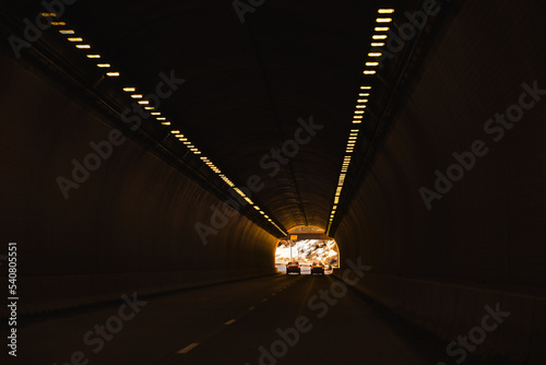 View of interstate highway tunnel through mountains in winter; exit in background photo