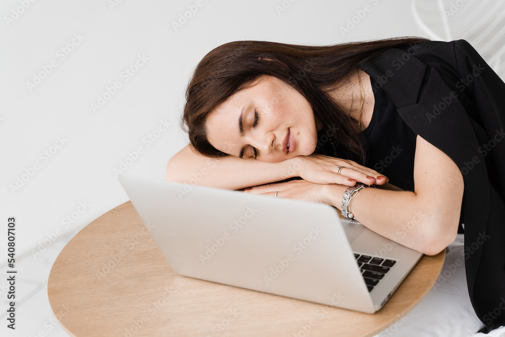 Sleeping girl with laptop on the table on white background. Tired young woman have a break at work and sleeping and relaxing at laptop on workplace due to overtime work. Sleeping girl with laptop on the table on white background. Tired young woman have a break at work and sleeping and relaxing at laptop on workplace due to overtime work.