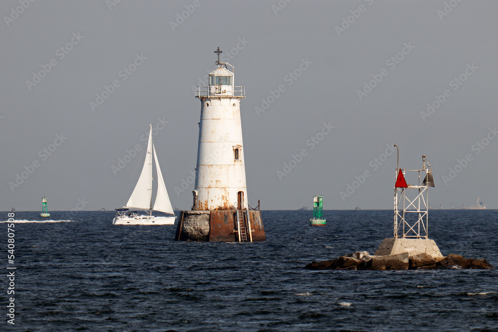 A sailboat sailing behind the Great Beds Lighthouse on the Raritan Bay in South Amboy, NJ