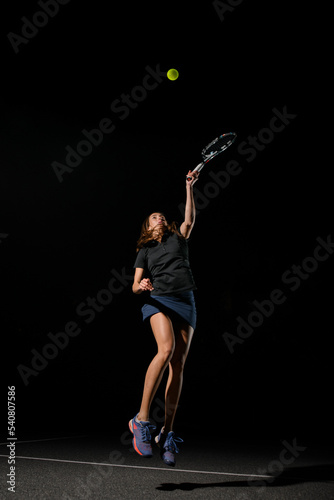 view of athletic woman with tennis racket in her hand bouncing to hit the tennis ball.