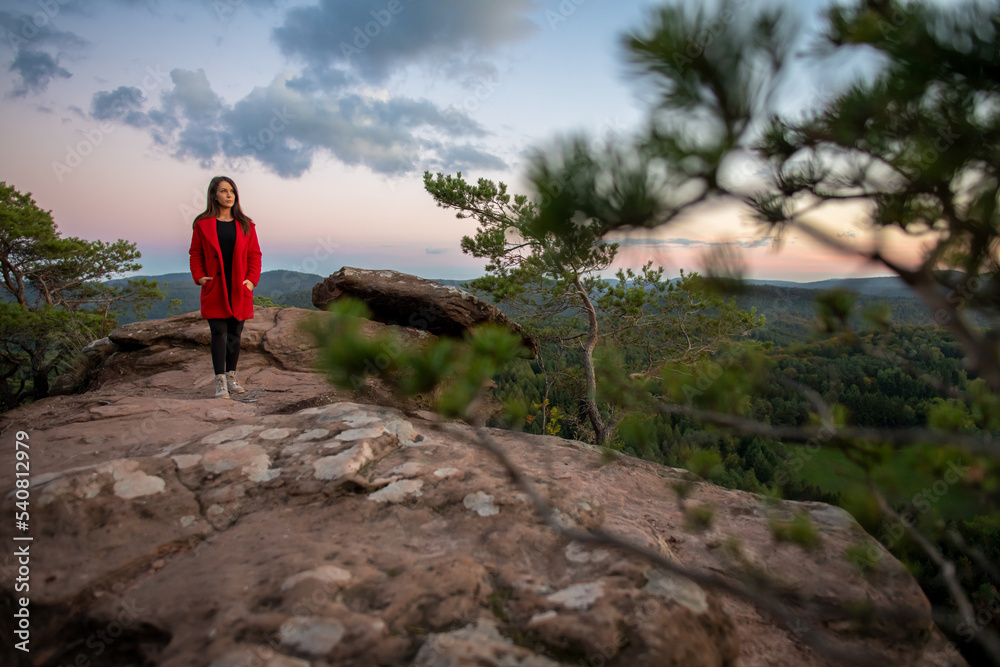 
Eine Frau genießt nach der Wanderung, vom Gipfel des Berges, die atemberaubende Aussicht der Landschaft mit einem wunderschönen Sonnenuntergang