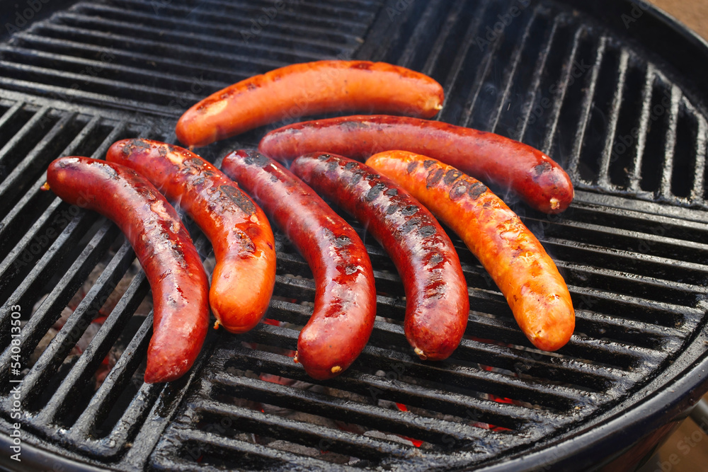 Traditionelle deutsche Bratwurst vom Grill angeboten als close-up auf einem Holzkohlegrill mit Feuer und Rauch Traditionelle deutsche Bratwurst vom Grill angeboten als close-up auf einem Holzkohlegrill mit Feuer und Rauch