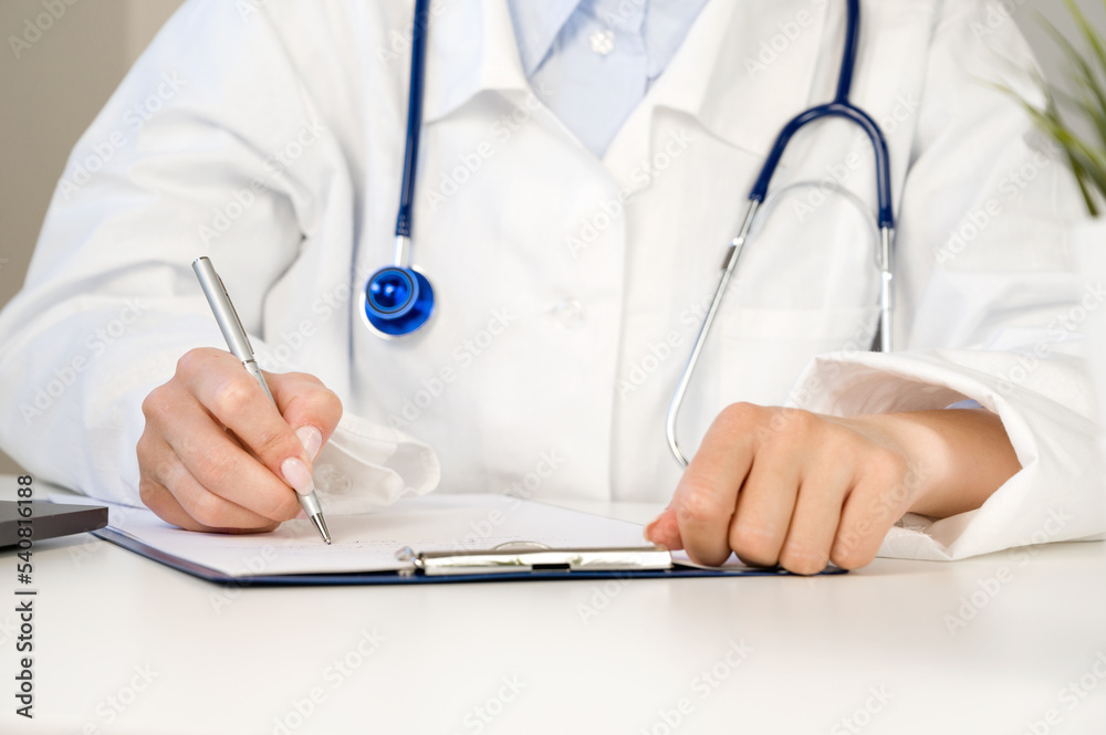 Closeup Doctor in a white labcoat writing out prescription or filling the form in the cabinet at hospital.Healthcare concept Closeup Doctor in a white labcoat writing out prescription or filling the form in the cabinet at hospital.Healthcare concept