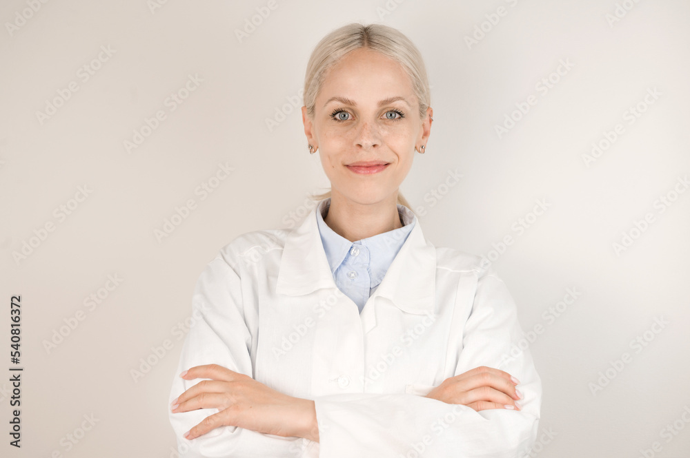 Young blonde doctor standing against gray background smiling at camera. Young blonde doctor standing against gray background smiling at camera.