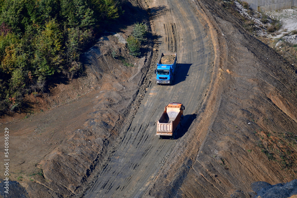 Large trucks transport excavated earth and rocks for highway construction Large trucks transport excavated earth and rocks for highway construction