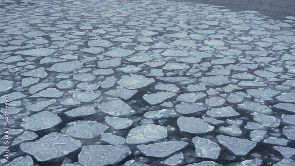 Pieces of ice on water surface. Puzzle of ice chunks. Ice on waves. Small pancake ice. View from vessel. Snowstorm. Pieces of ice on water surface. Puzzle of ice chunks. Ice on waves. Small pancake ice. View from vessel. Snowstorm.