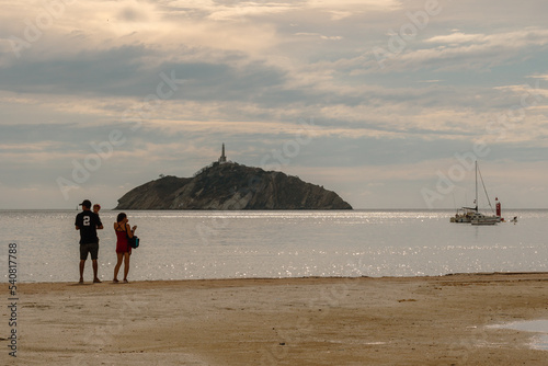 Tourists in the beautiful sunset light on the beach of Santa Marta, Colombia, with the Isla el Morro in the background. © Bruno