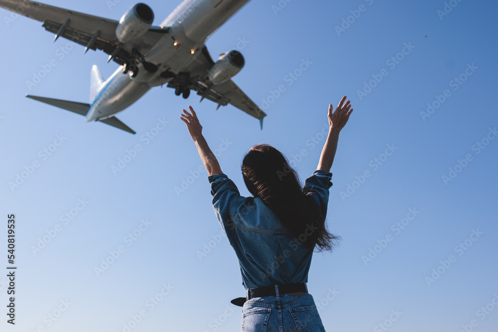 Girl and airplane in flight, landscape with woman standing with hands raised up, waving arms and flying passenger airplane, female tourist and landing commercial aircraft, summer sunny day Girl and airplane in flight, landscape with woman standing with hands raised up, waving arms and flying passenger airplane, female tourist and landing commercial aircraft, summer sunny day