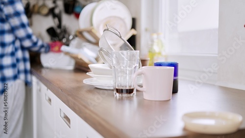 Konstfotografi a pile dirty dishes on a kitchen counter with a person standing in the background