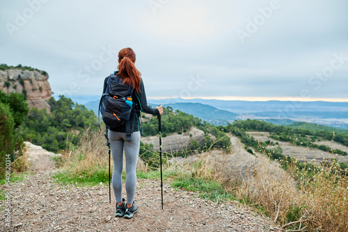 Ginger tourist with ski sticks enjoying the view