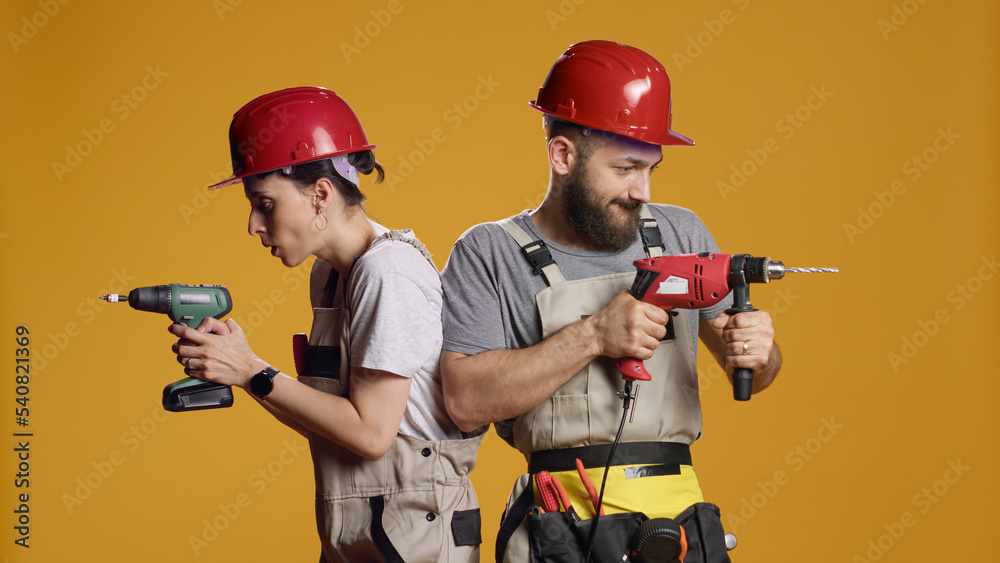 Construction workers using power drill gun to work on industrial