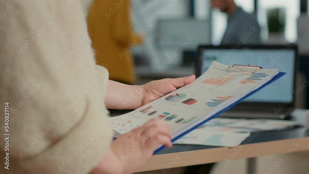 Closeup of woman hands holding clipboard with papers looking at pie chart and business profit data in startup office. Focused employee analyzing key performance indicators reading turnover statistics. Closeup of woman hands holding clipboard with papers looking at pie chart and business profit data in startup office. Focused employee analyzing key performance indicators reading turnover statistics.