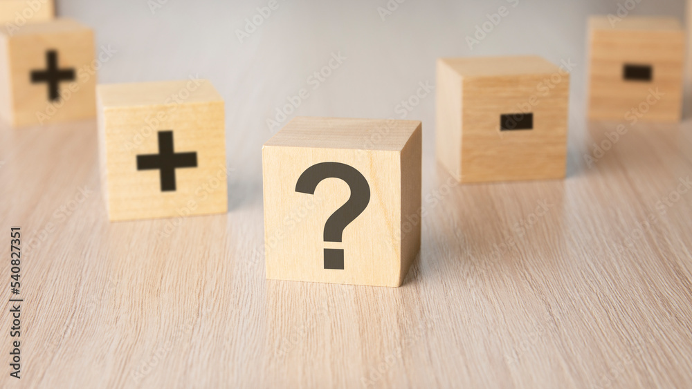 sign question mark, plus, minus sign on the faces of a wooden cube ...