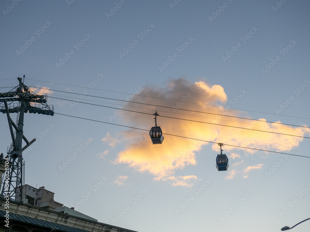 Ropeway. Esaltor booths against the background of a golden cloud. Silhouettes of cable car cabins in the sky. Ropeway. Esaltor booths against the background of a golden cloud. Silhouettes of cable car cabins in the sky.