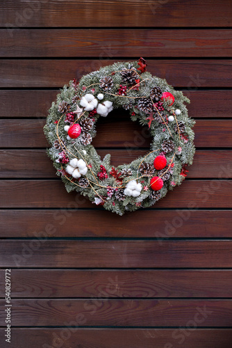 Christmas wreath with nobilis fir , cones, berries, red apples and stars on wooden background