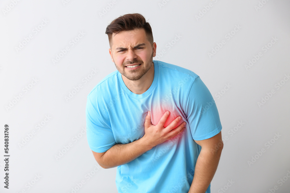 Young man having heart attack on light background Young man having heart attack on light background